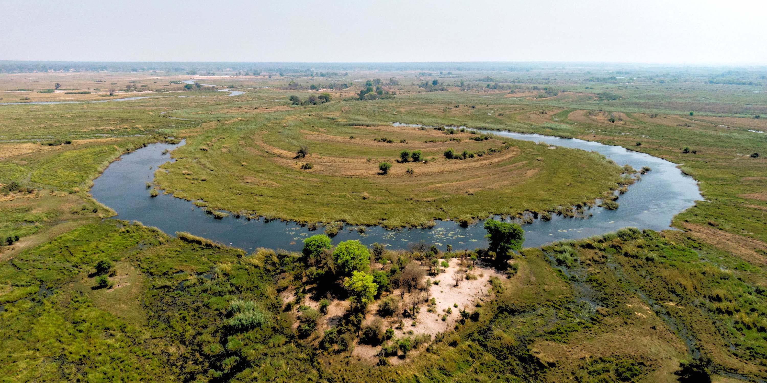 Aerial view of a bend in a wide river in a green landscape.