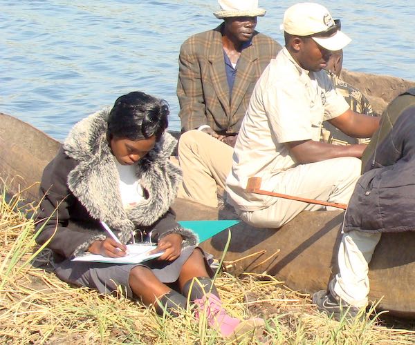 A community fisheries inspector records details of the catch as a group of fishmen unload their boat.