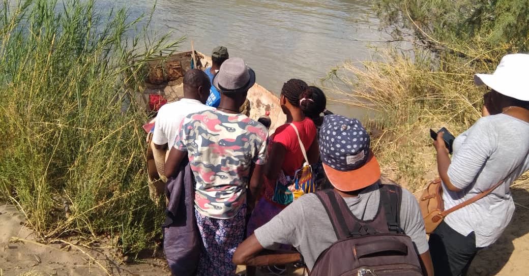 Researchers boarding a wooden boat to cross the Kunene river.