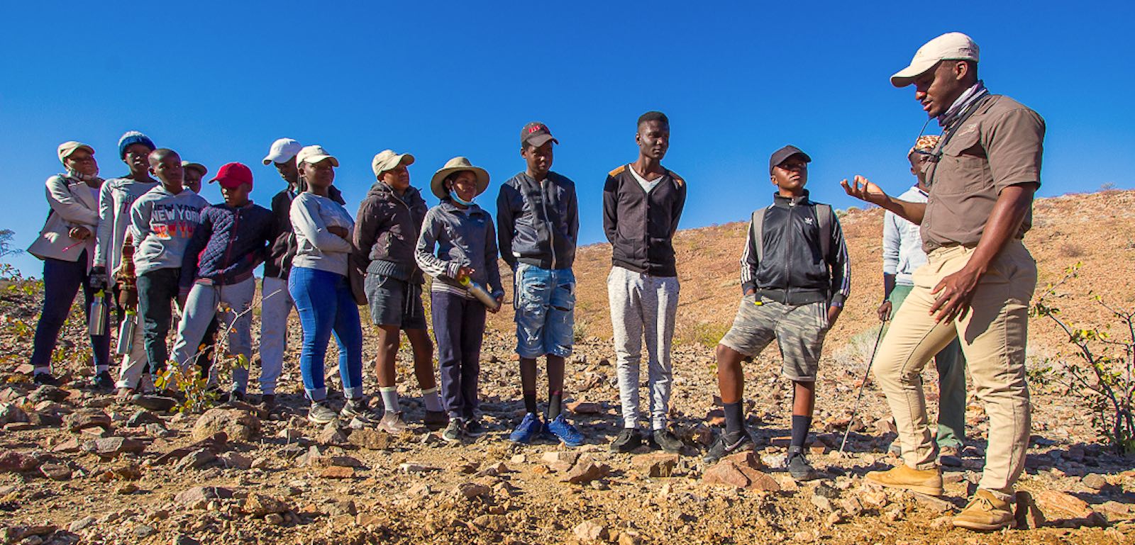 A group of Namibian children listen to a local guide.