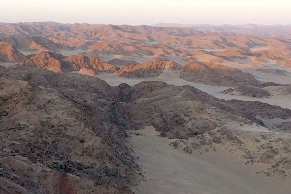 The red rocks of the desert mountains of Namibia gleam under the rising sun.