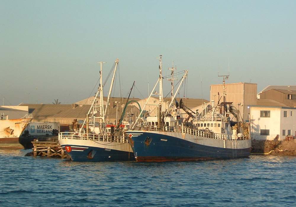 Two fishng vessels moored at a quay.