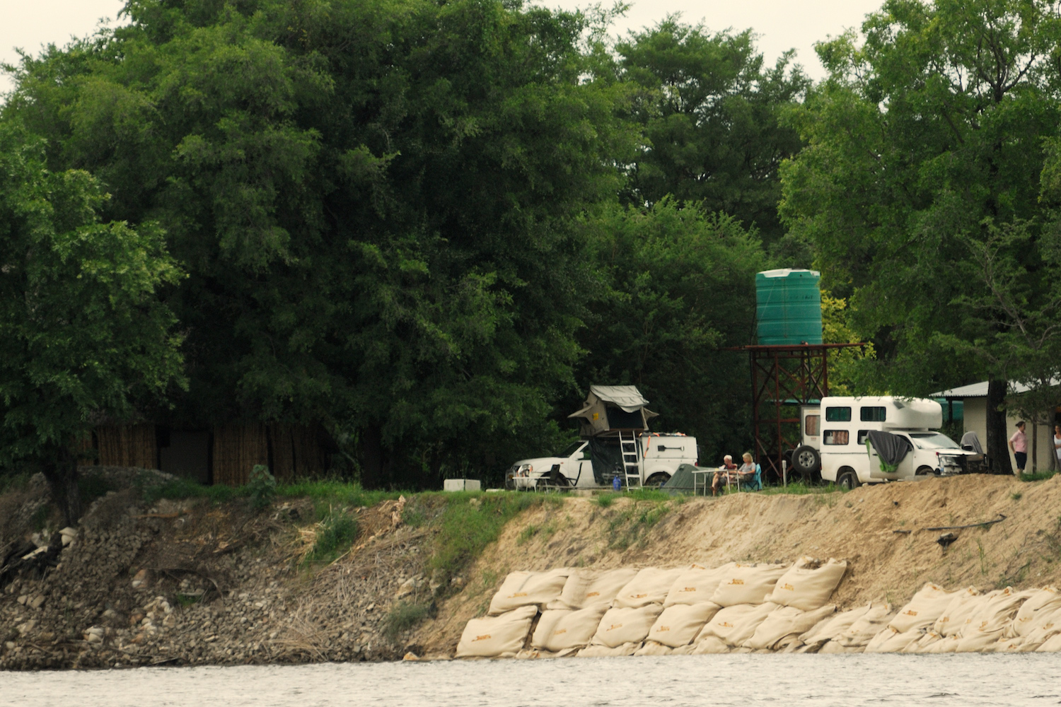 A group of tourists camping on the riverbank.