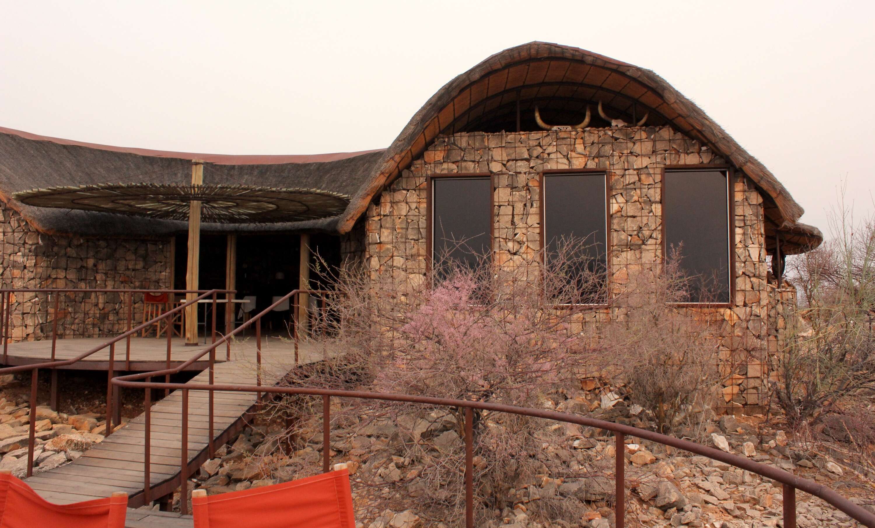 A wooden deck leads over the rocks to the main lodge building.