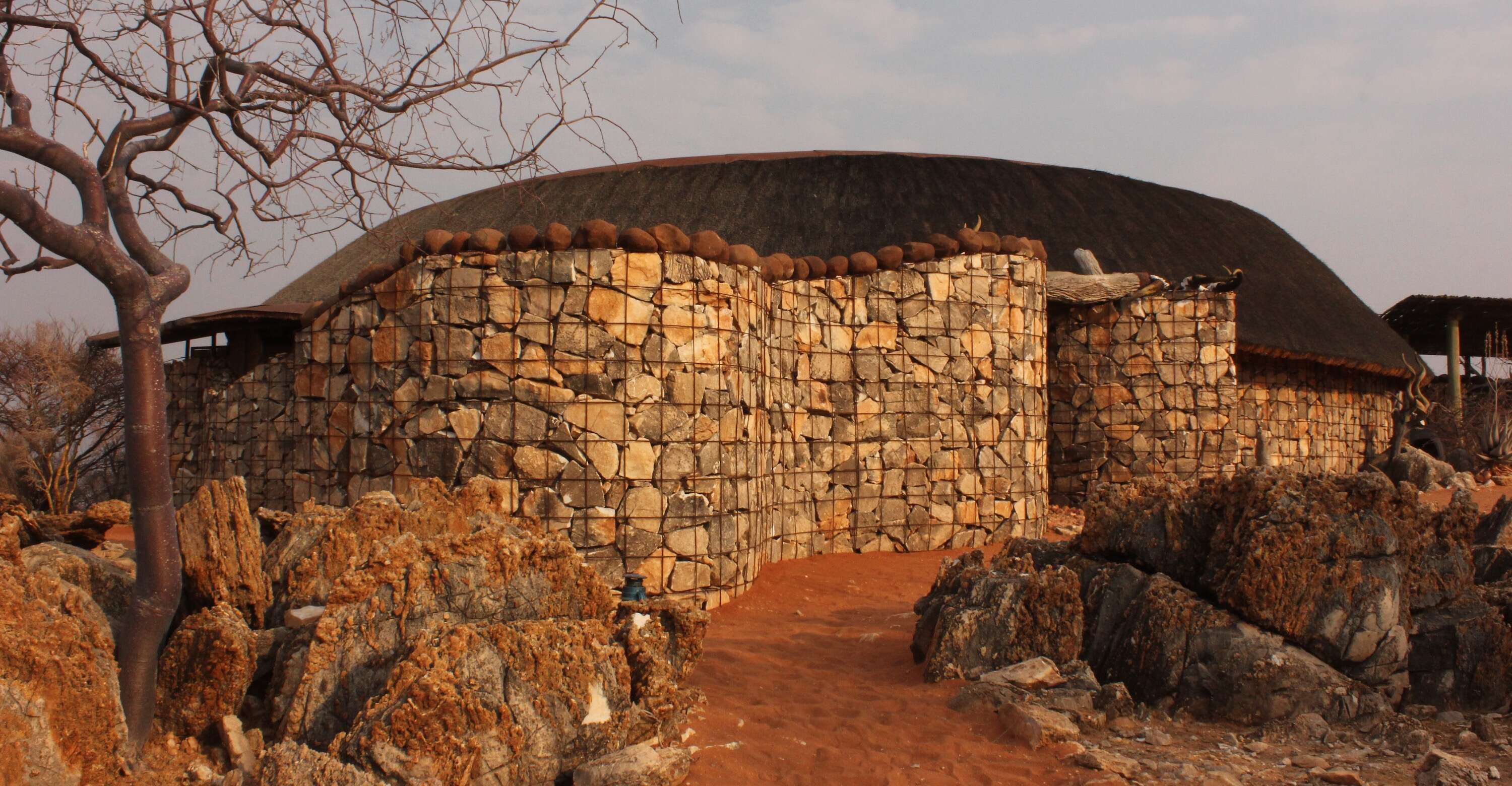 A lodge built from local stone and thatch nestled into the landscape.