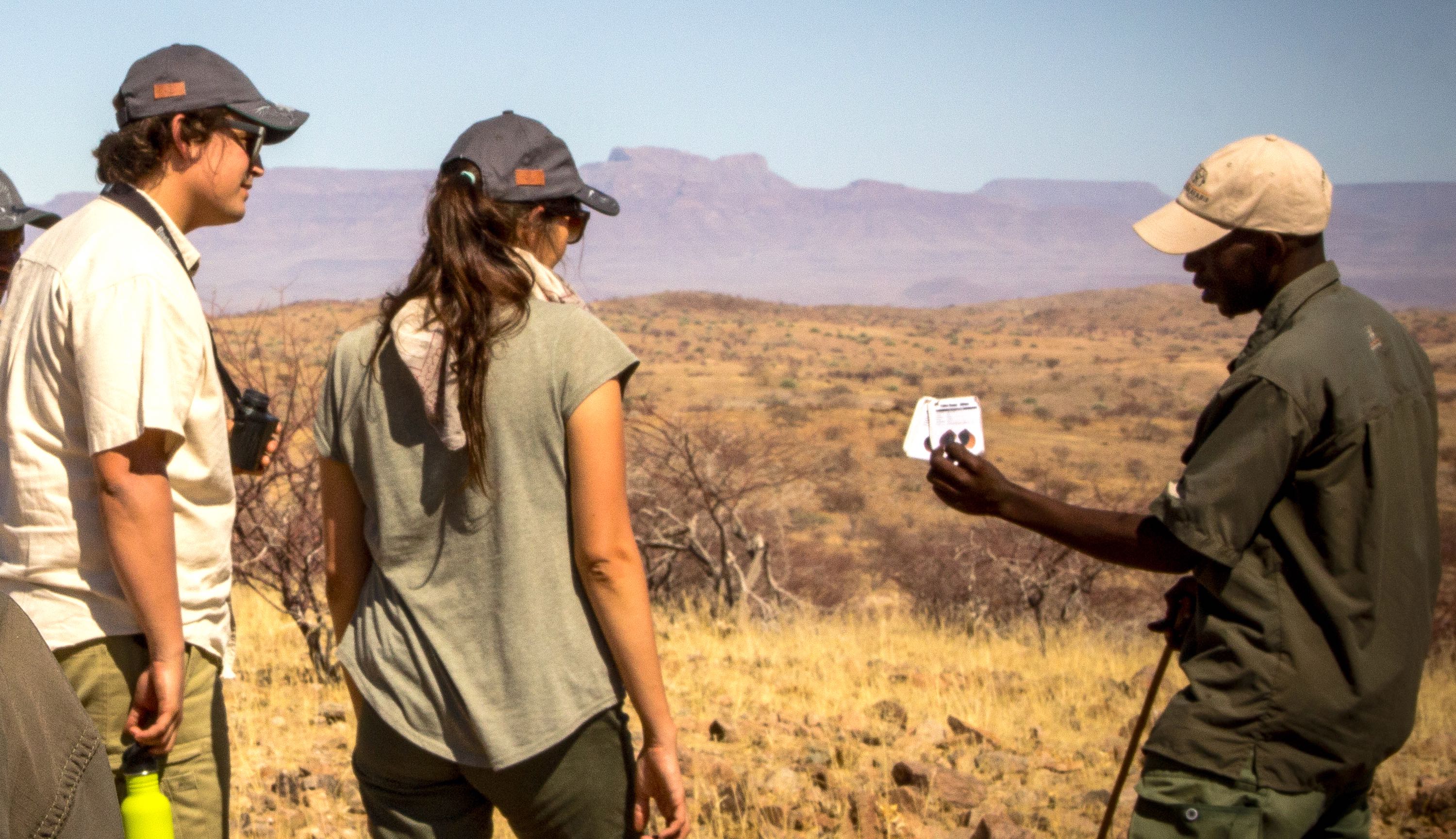 A ranger explains to to identify individual rhinos to two tourists.
