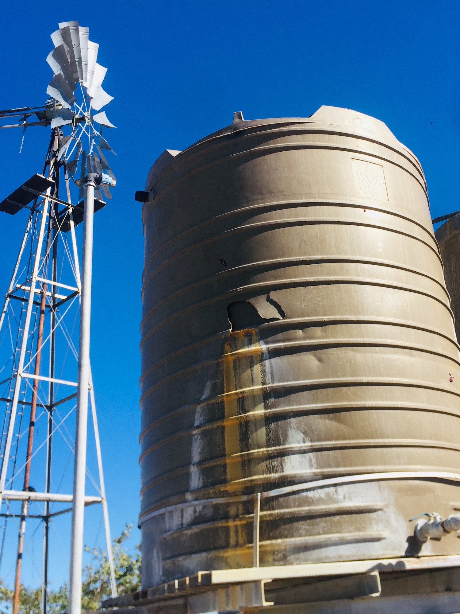 A large cylindrical water tank with a hole smashed into the side.