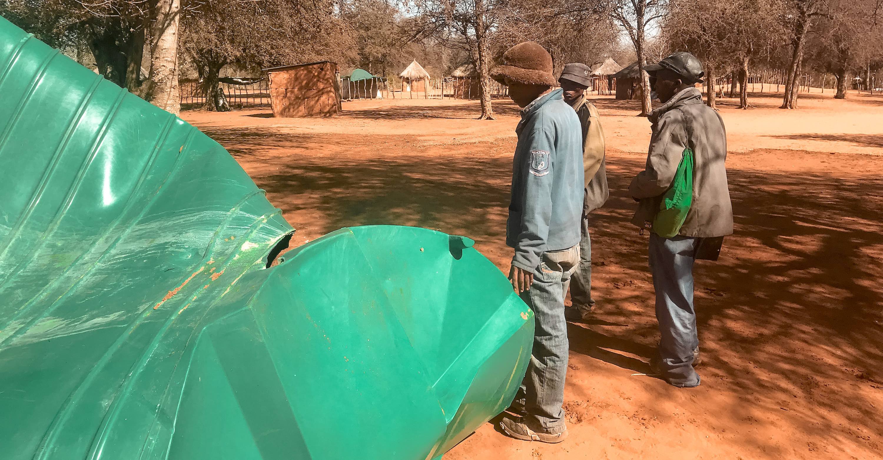 Three men looking at a destroyed water tank.