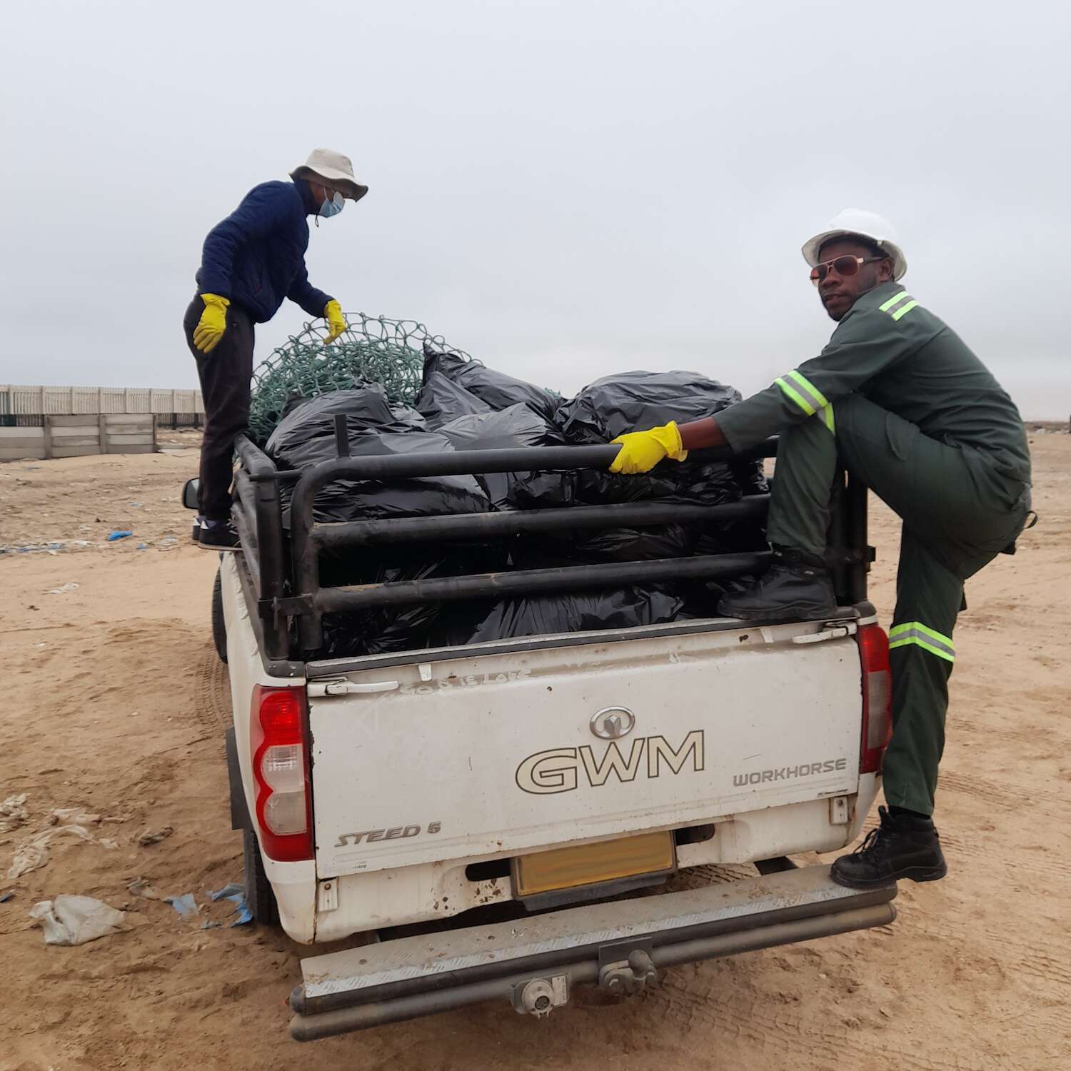 Two people and a bakkie full of rubbish sacks.