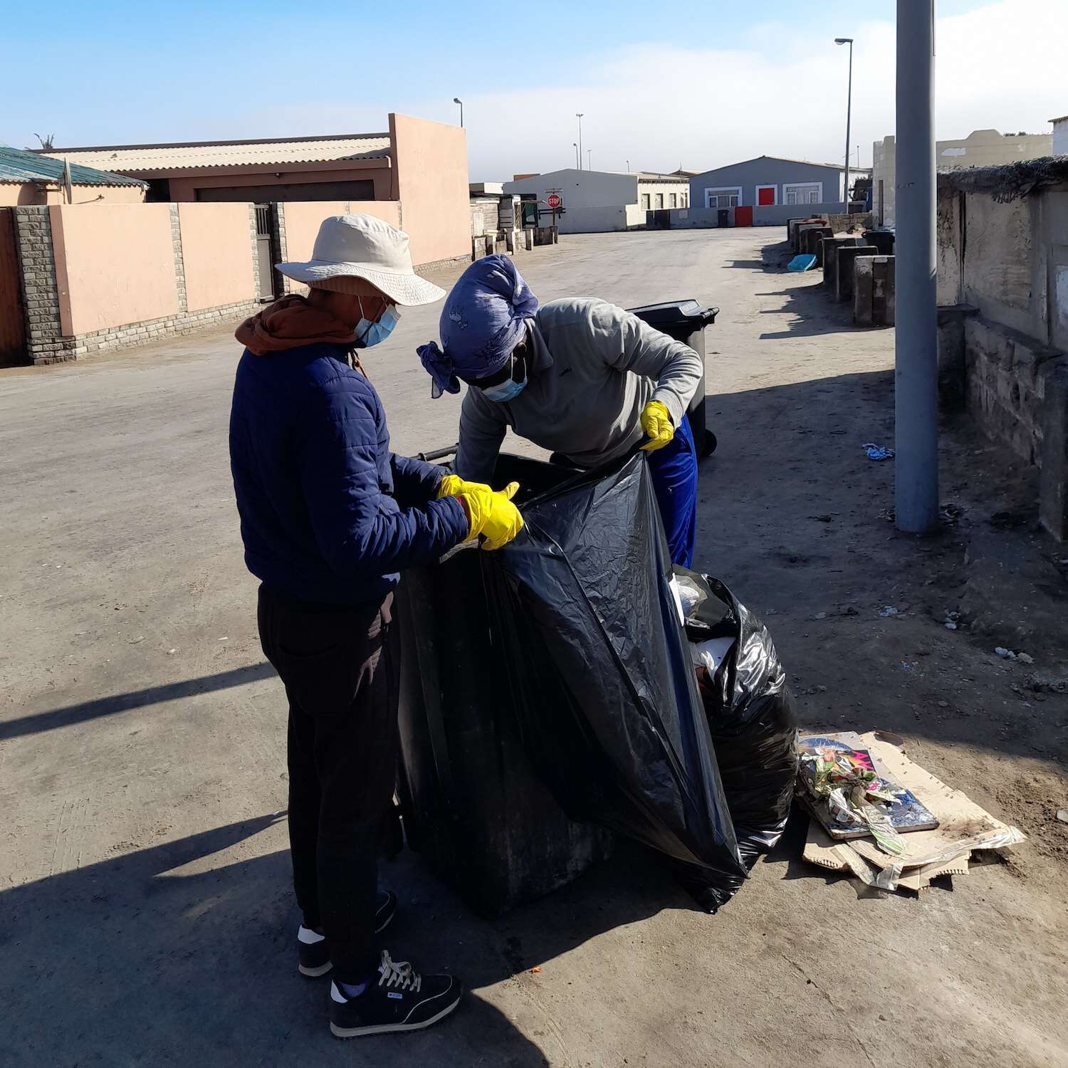 Two people checking the contents of a rubbish sack.