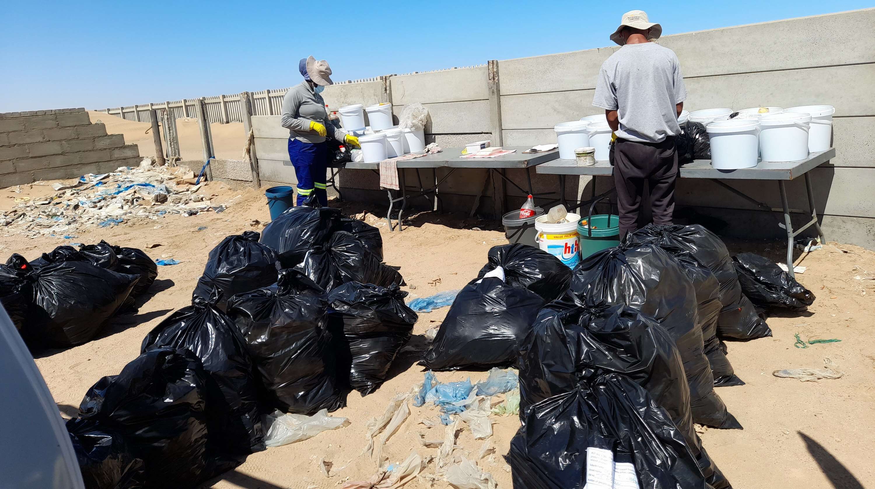 Two people sorting through a pile of rubbish sacks.