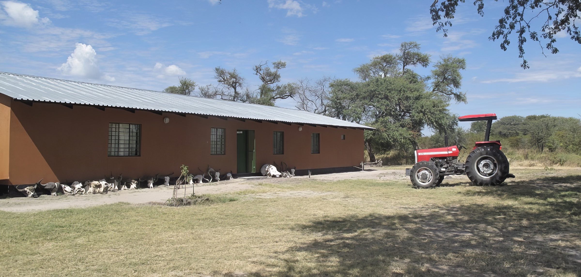 A red tractor parked in front of a single story building.