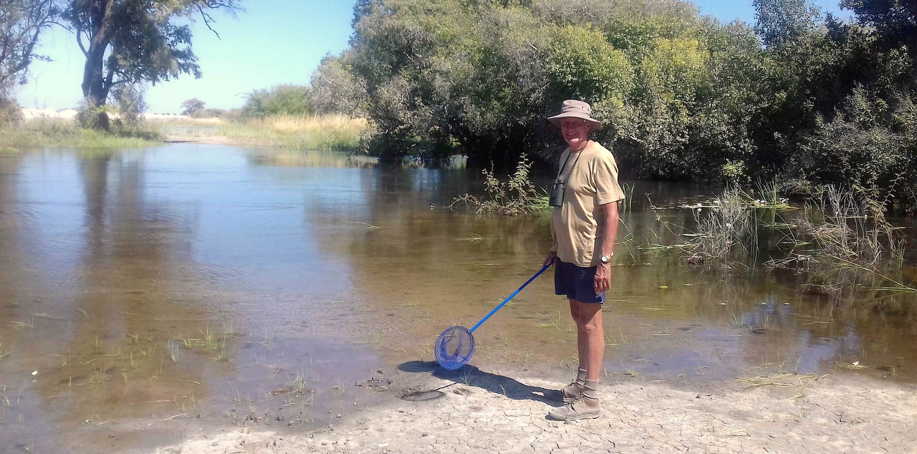 Dave Ward standing by a small lake, while holding a net on a pole.