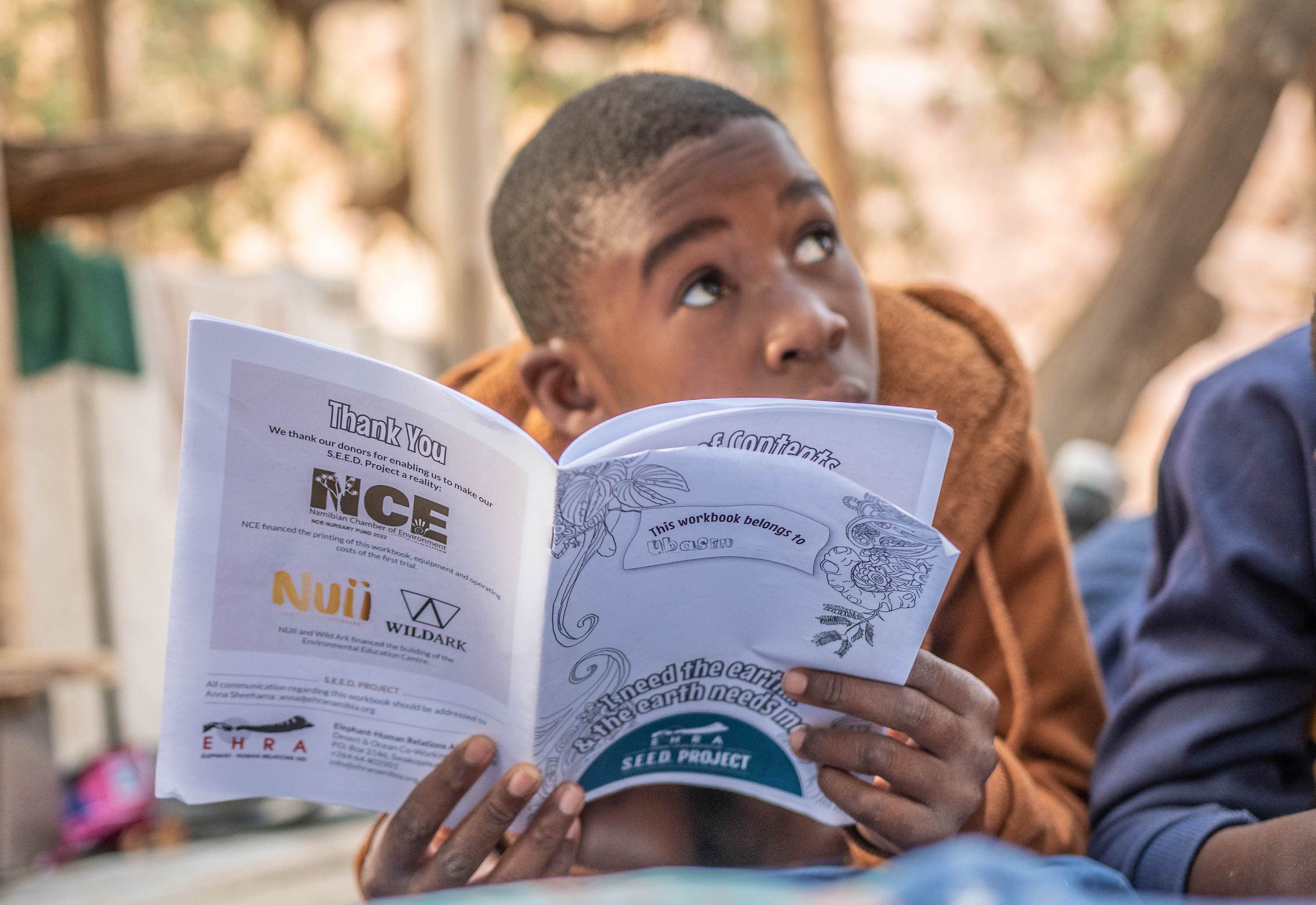 A child looks up while reading the EHRA education booklet.