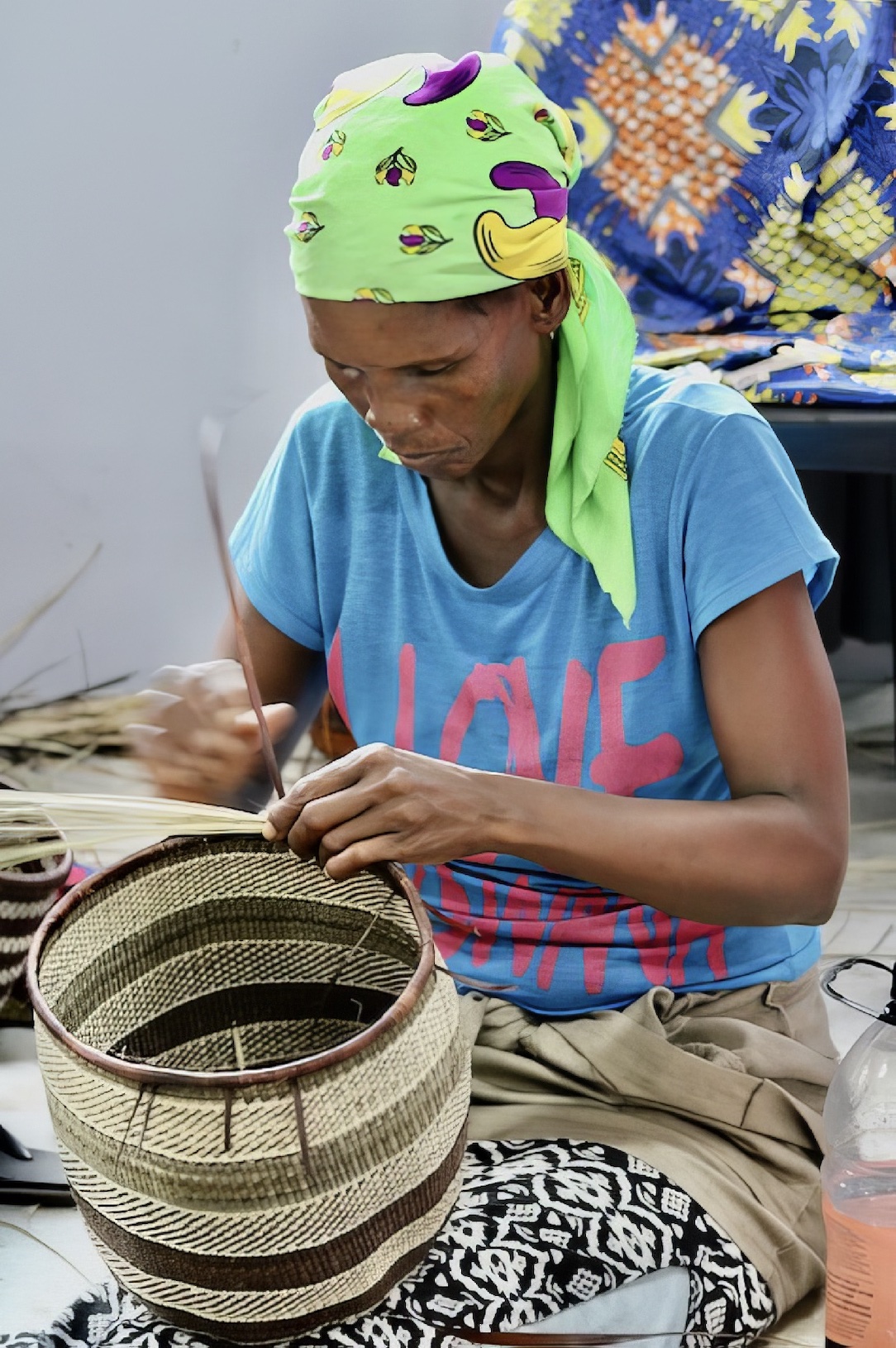 A San woman focusses intently on the basket she is weaving.