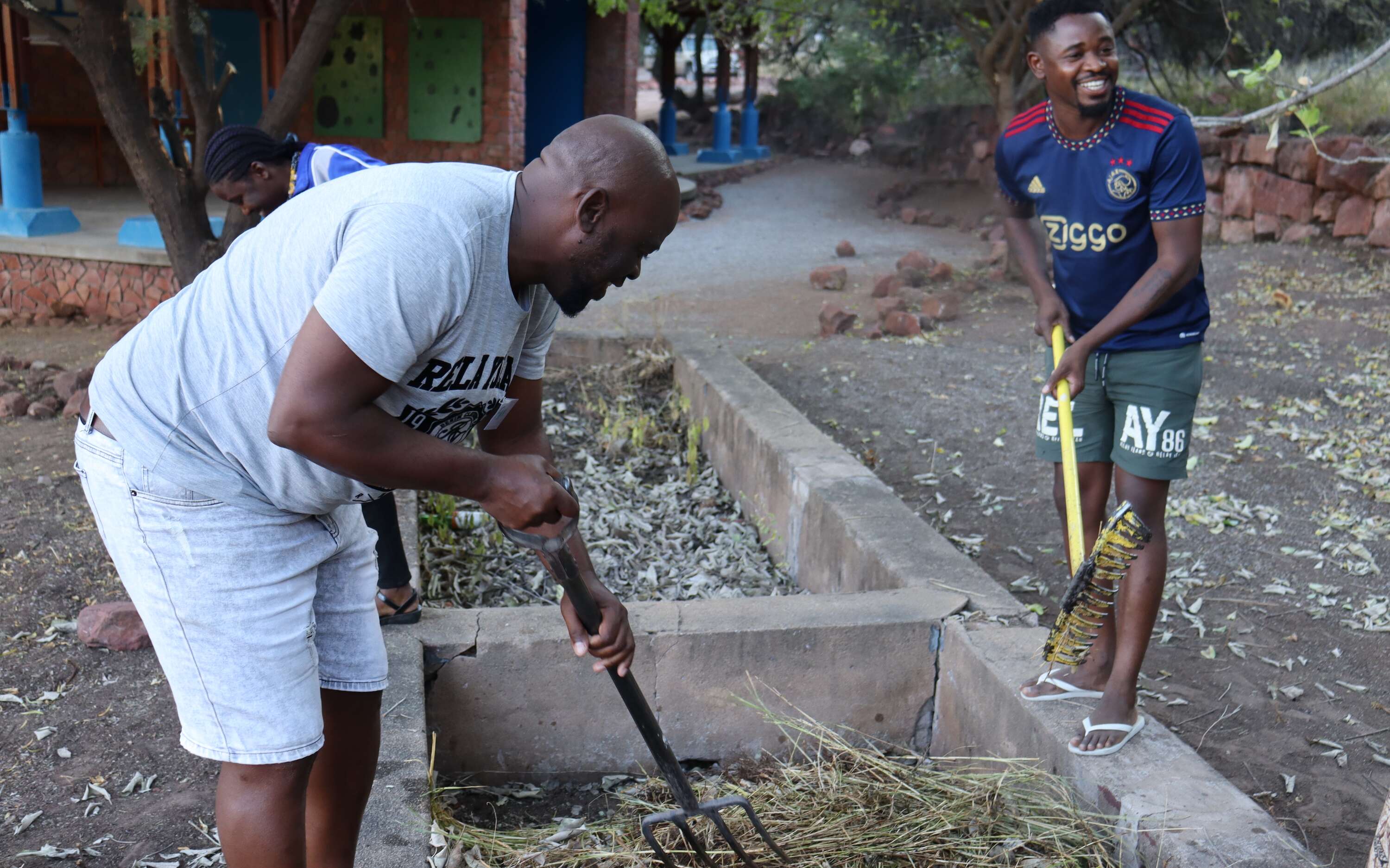 Two men raking a garden.