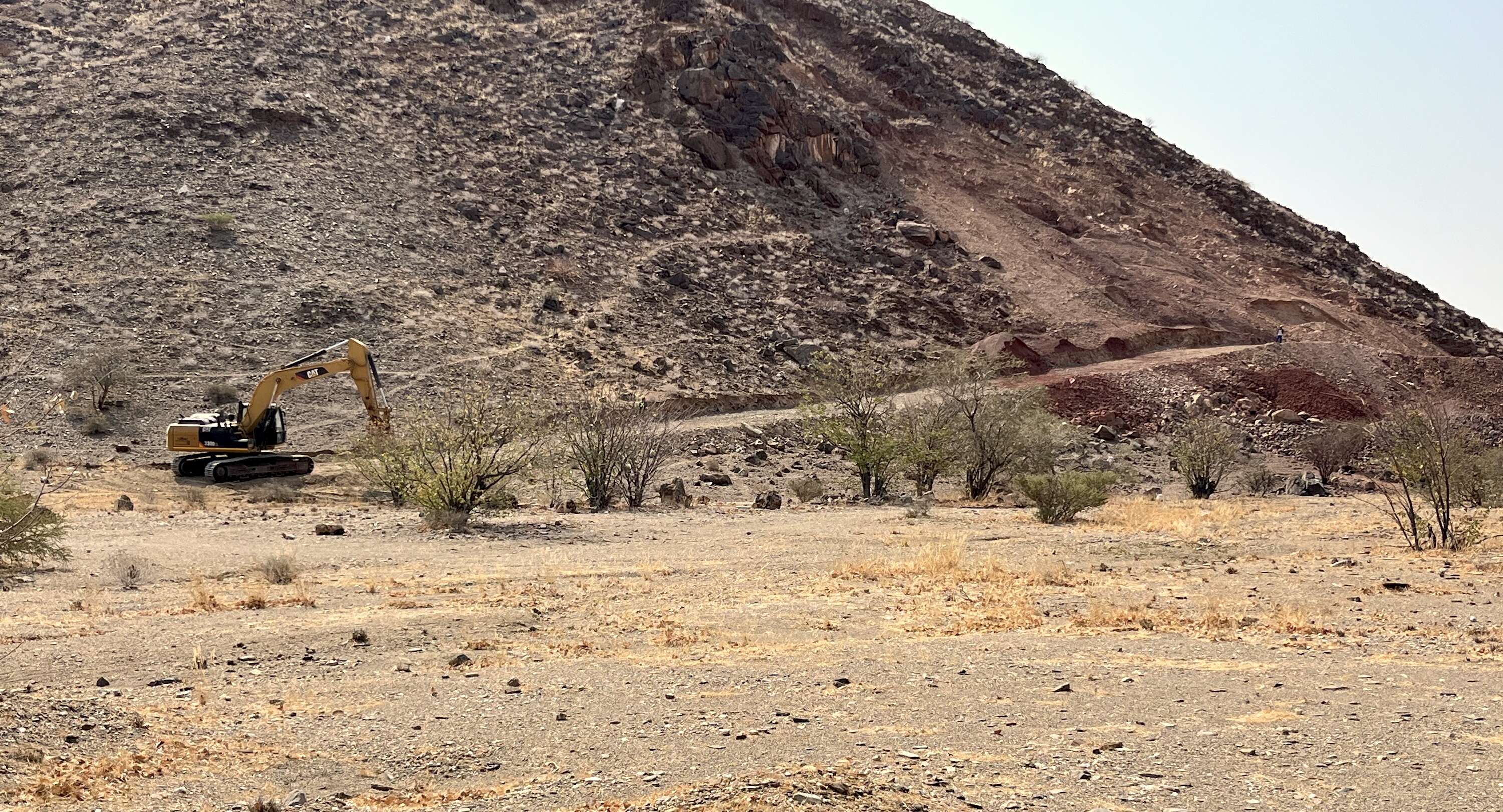 Mechanical digger and a large road in the desert.