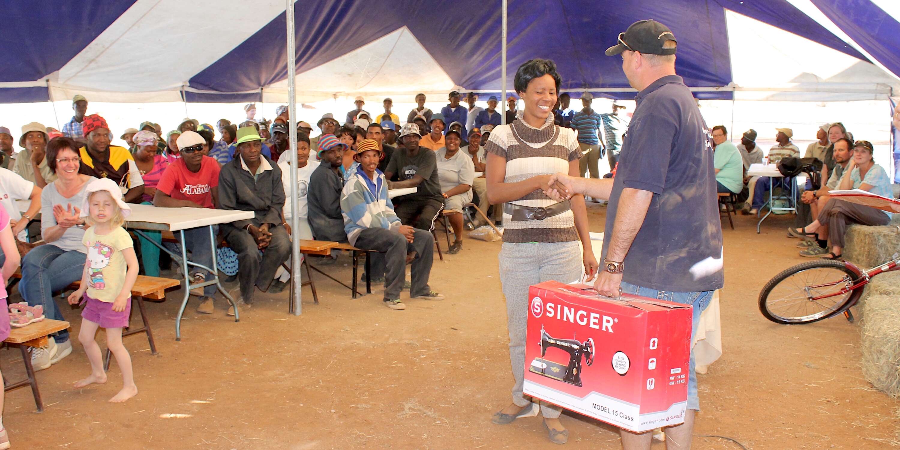 A crowd watches as a prize is presented to a woman.