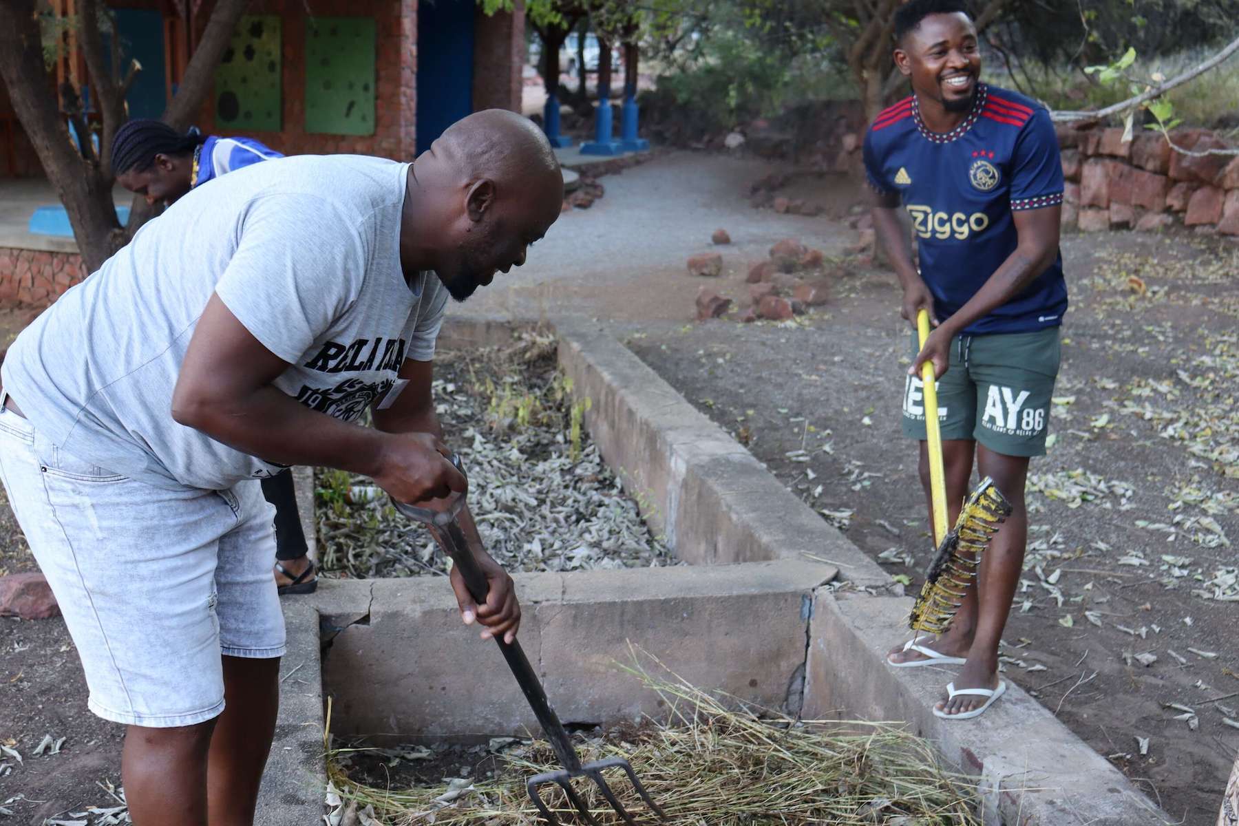 Two men raking a garden.