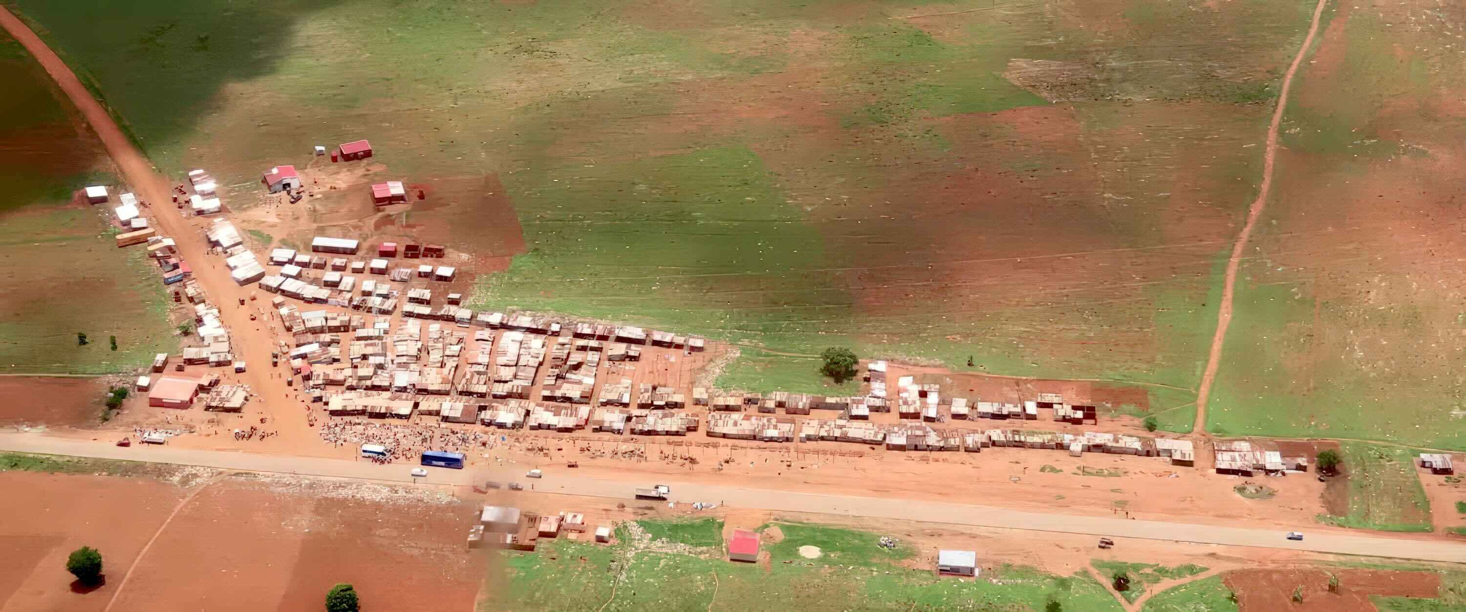 Shacks, vehicles and people cluster at a road junction.