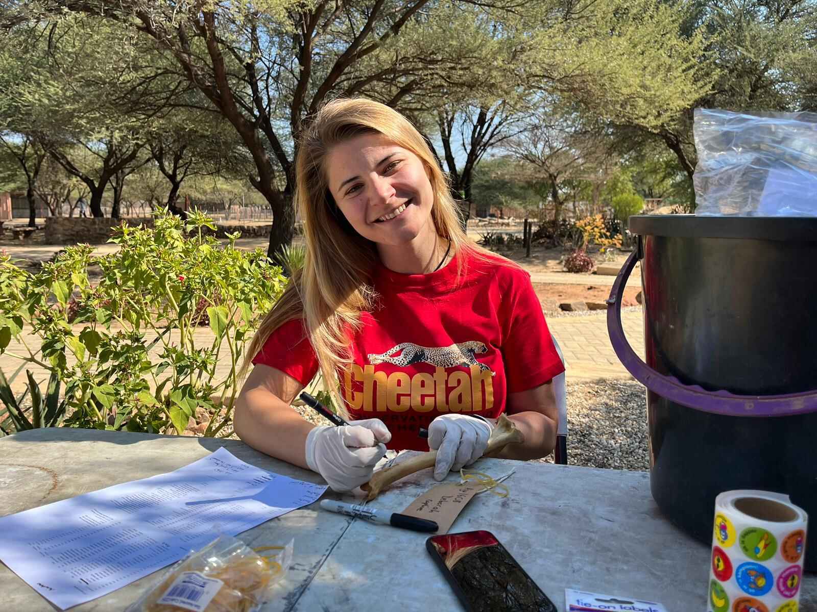 A woman smiles at the camera while holding a pen and a small bone.