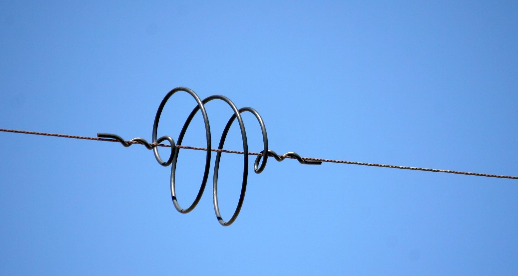 A coil of wire looped around a power cable.