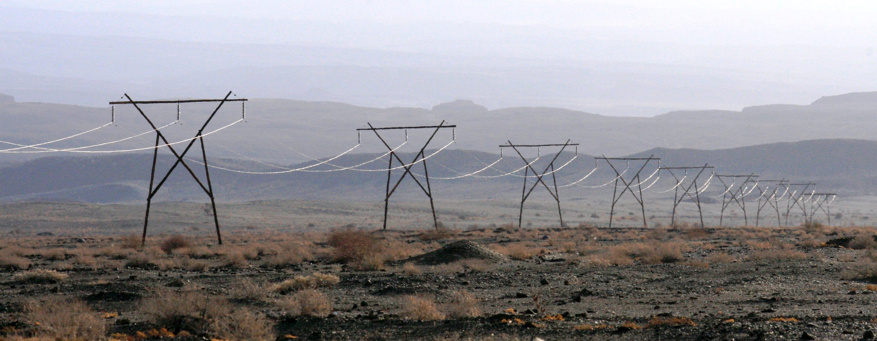 A line of high-voltage pylons stride into the distance.
