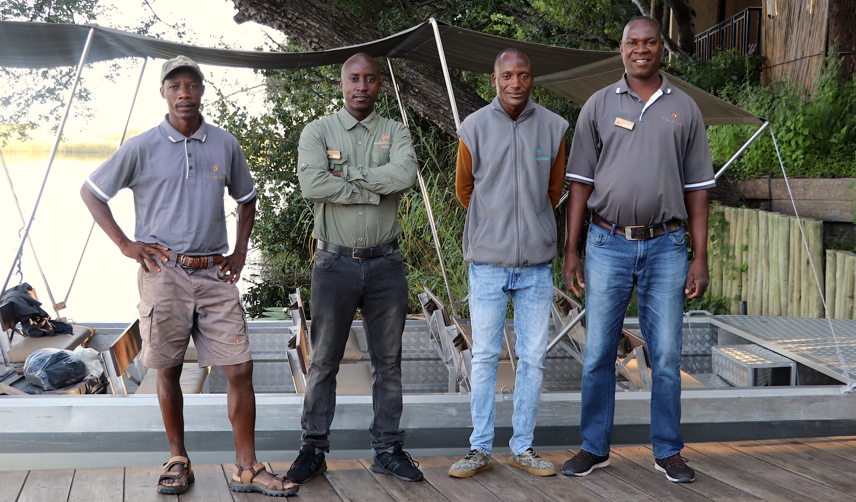 Four happy looking men pose in front of a boat.