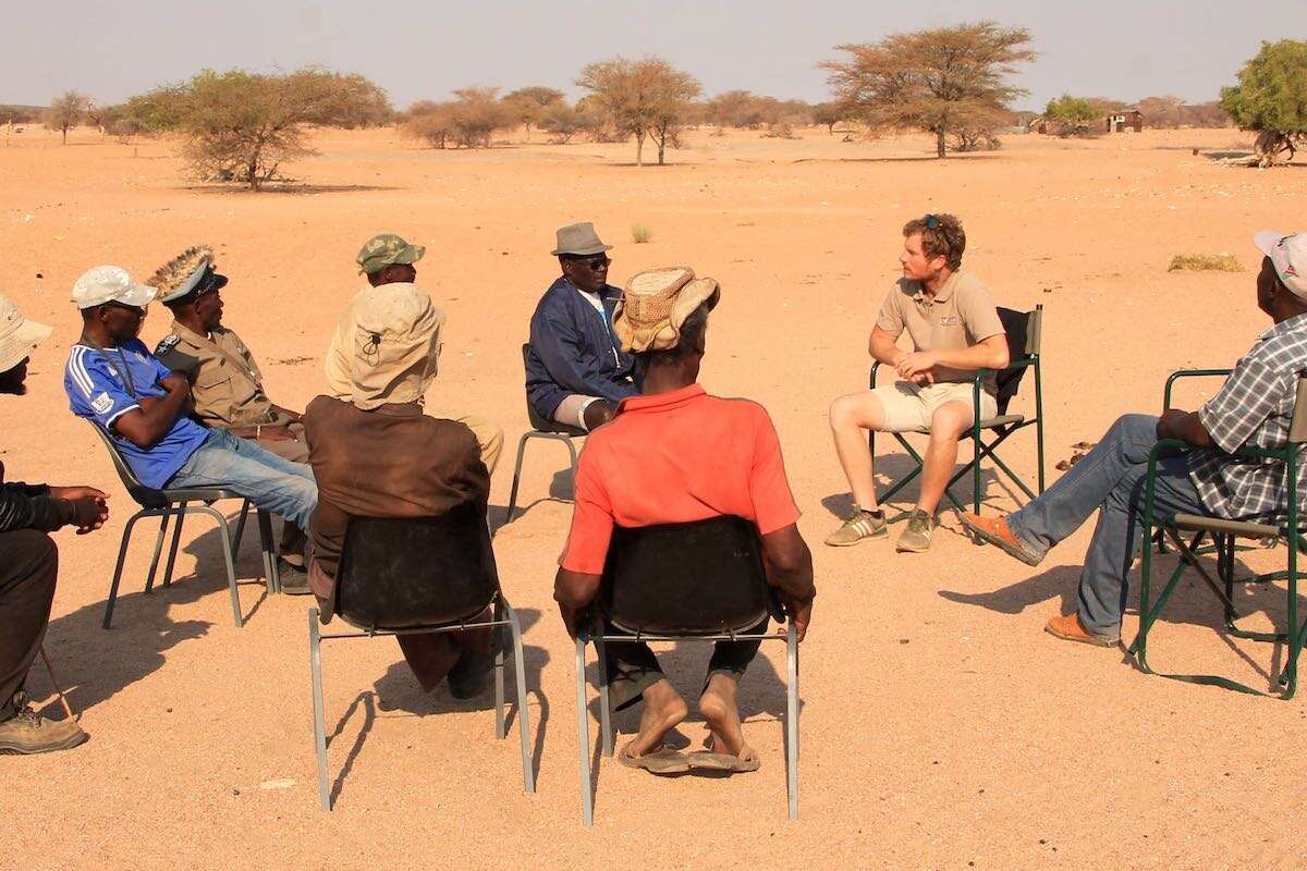 A group of people sitting on a circle of chairs in the desert - a meeting with a view!