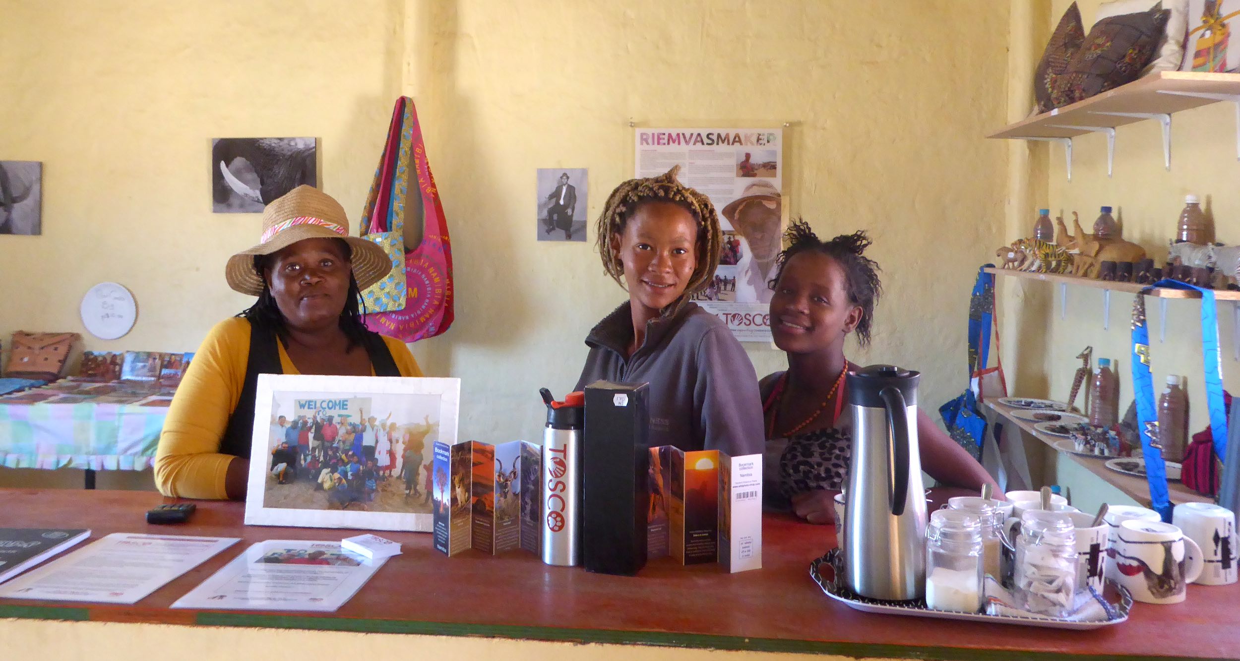 Three local women pose behind the counter of their information and craft centre.