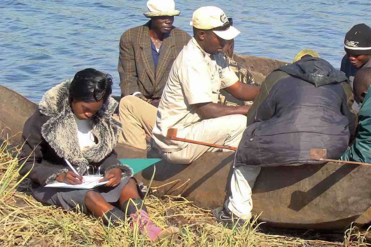 A community fisheries inspector records details of the catch as a group of fishmen unload their boat.