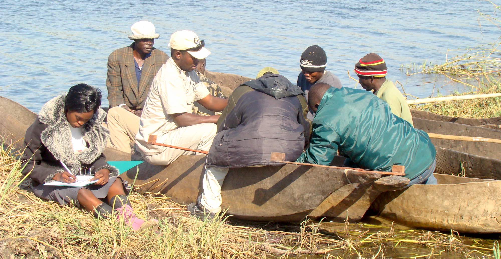 A community fisheries inspector records details of the catch as a group of fishmen unload their boat.