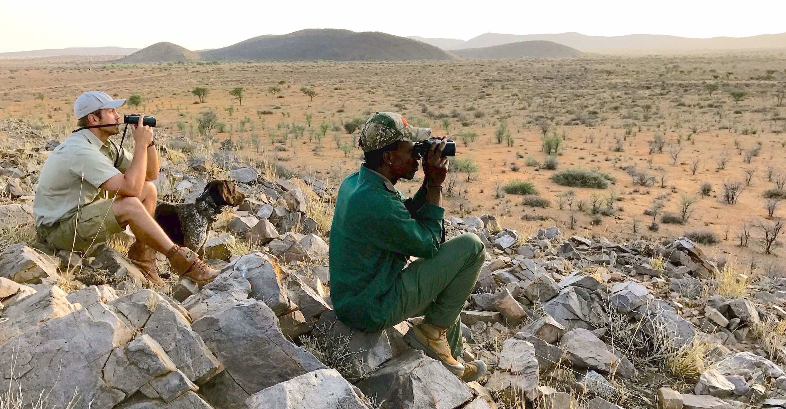 A hunter and his guide look through their binoculars.