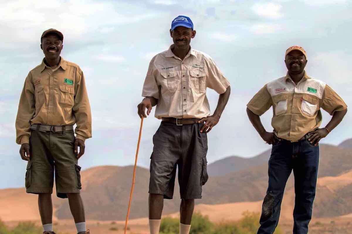 Three Community Game Guards smile at the camera.