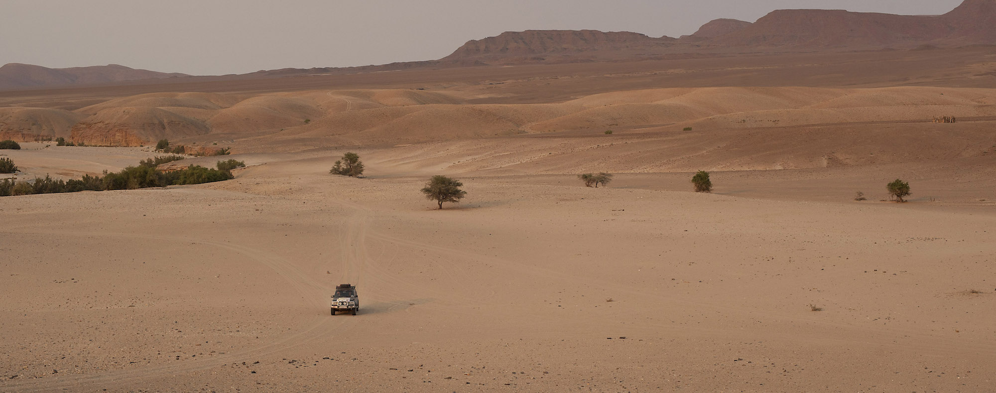 A lone 4x4 drives across the vast landscape of northern Namibia.