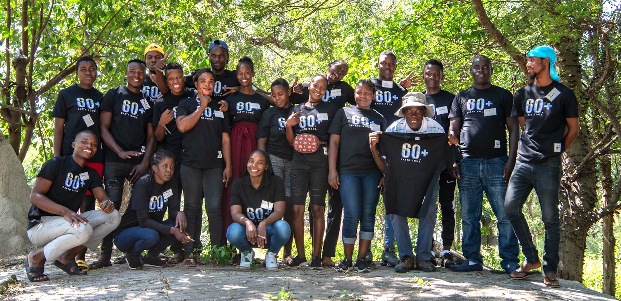 A group of young Namibians standing under tress and smiling broadly.